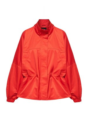 Veste rouge vif à manches longues avec col haut, poignets élastiques et taille cintrée, exposée sur un cintre blanc.