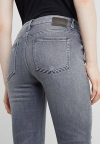 Grå denimjeans med en mjuk textur, medelhög midja, femficksdesign och en liten läderetikett på baksidan av midjebandet.