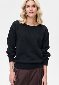 Czarny sweter z dzianiny z wzorem diamentowym z małymi wyci�ęciami. Zaprojektowany z szerokim dekoltem i opuszczonymi ramionami, teksturowane mankiety.