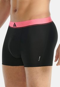 Svarta träningsshorts med ett strukturerat rosa midjeband. Har Adidas-logotypen och "Climacool"-etiketten på sidan. Formpassande design.