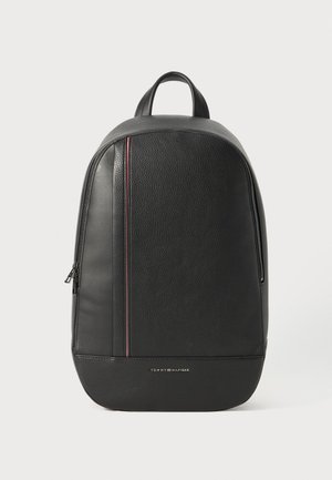 Black leather backpack with textured finish, slim shape, top handle, and a subtle red and white stripe detail on the side.
