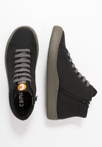 Czarne sneakersy za kostkę z teksturowaną, płócienną cholewką, szarymi sznurowadłami, bocznym zamkiem błyskawicznym oraz trwałą, grubą gumową podeszwą. Posiada logo marki na języku.