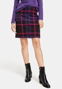 Gonna a quadri in misto lana nei colori nero, viola e rosa; design slim fit; lunghezza sopra il ginocchio; abbinata a stivaletti neri in pelle con tacco a blocco.