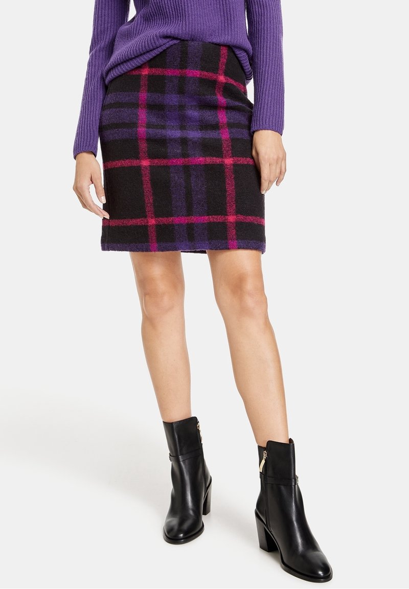 Gonna a quadri in misto lana nei colori nero, viola e rosa; design slim fit; lunghezza sopra il ginocchio; abbinata a stivaletti neri in pelle con tacco a blocco.