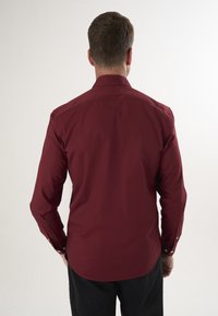 Burgunderfarbendes Button-up-Hemd aus Baumwolle mit langen Ärmeln, einem Standardkragen und einem taillierten Schnitt mit Schulternähten.