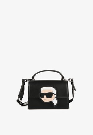 Bolsa estruturada preta em pele com um design de rosto de cartoon na frente, apresentando óculos de sol e um detalhe de rabo de cavalo branco.