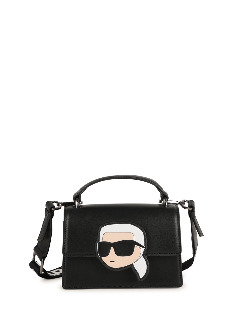 Borsa strutturata nera in pelle con un design di faccia di cartone animato sulla parte anteriore, caratterizzata da occhiali da sole e un accento di coda di cavallo bianca.
