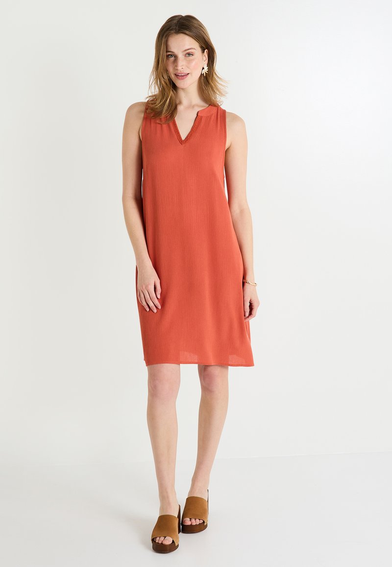 Vestido sin mangas de color óxido con escote en V, tejido texturizado y forma en A. Combinado con mule de punta abierta en color marrón. Diseño simple y casual.