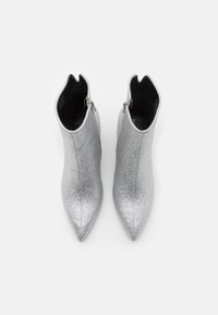 Botines plateados y brillantes con diseño de punta afilada. Presentan una cremallera lateral y un revestimiento interior suave.
