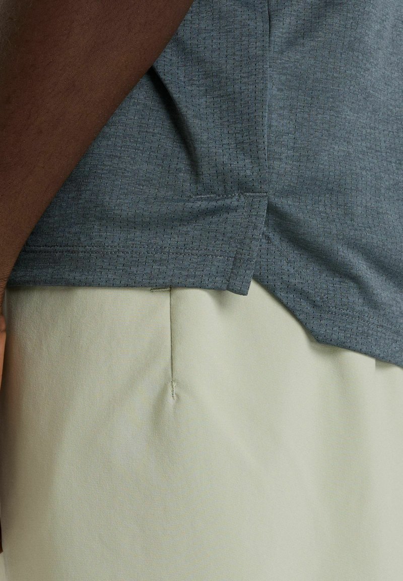 Gray textured fabric top with a sharp hem, paired with light beige pants featuring a center seam and soft material.