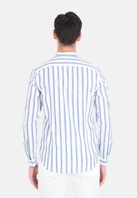 Camicia bianca a maniche lunghe con righe verticali blu, caratterizzata da un colletto semplice e polsini abbottonati, realizzata in tessuto leggero.