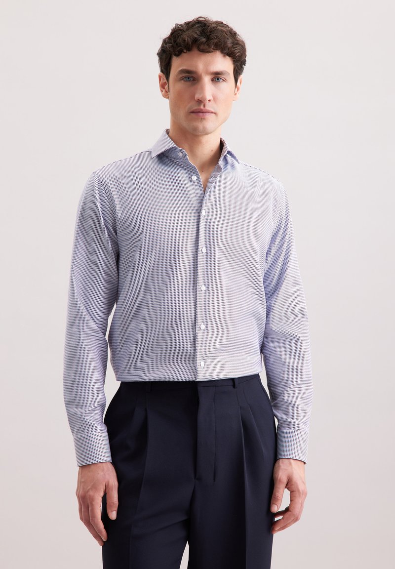 Camicia da uomo a maniche lunghe con bottoni di colore azzurro chiaro, con un piccolo motivo a quadretti blu navy, caratterizzata da un colletto classico e maniche ripiegate, abbinata a pantaloni scuri.