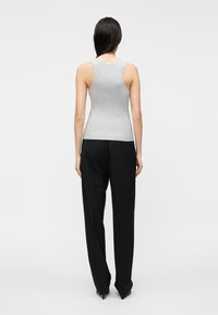 Gr�å ribbet tanktop med brede stropper, tætsiddende design og kontrasterende sorte bukser med vide ben. Glat tekstur og minimalistisk stil.