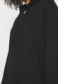 Svart huva sweatshirt i bomull, med en framficka, dragsko och en liten logotyp på bröstet.