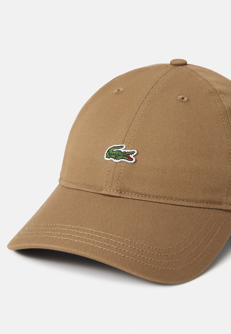 Braune Baumwoll-Baseballmütze mit gebogenem Schirm, ausgestattet mit einem gestickten grünen Krokodil-Logo und sichtbaren Nähten.