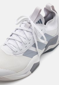 Scarpa sportiva Adidas bianca e grigia con lacci, tomaia in maglia e suola spessa con supporto Torsion System.