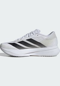 Fehér sportcipő, lélegző hálós felsőrésszel, három fekete ferde csíkkal, textúrázott részletekkel és párnázott talppal, amelyen a "LIGHTSTRIKE" felirat található.