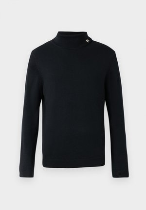 Must musträi turtleneck-sviiter, millel on pikad varrukad, ribikätised ja krae ning väike metalliline logo aktsent krael.