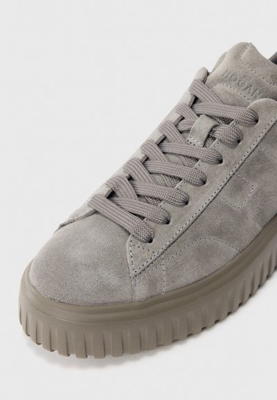 Sneaker in suede grigio chiaro con suola in gomma spessa e scanalata e lacci grigi abbinati, vista inclinata che mostra la cucitura laterale e i dettagli dei lacci.