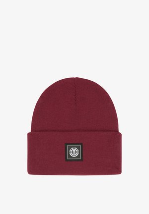 Burgundy knit beanie with a folded cuff and a black square patch featuring a white logo. Soft texture, rounded top, and solid color design.