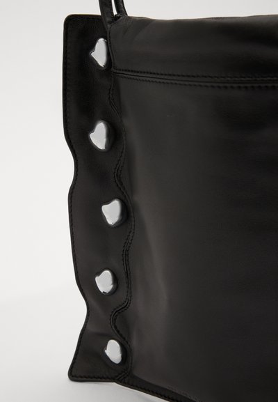 Black leather bag with a wavy edge, featuring silver heart-shaped accents and contrasting stitching along the sides.