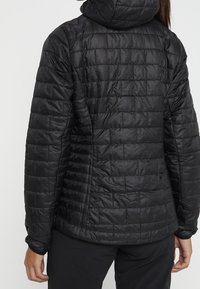 Svart puffig jacka med hög krage, med quiltade paneler och en jämn textur. Designen är åtsittande, med långa ärmar och utan synliga detaljer.