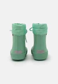 Bottes de pluie en caoutchouc vertes avec un col rembourré, des accents en laçage et des semelles grises texturées ; elles possèdent des détails réfléchissants à l'arrière.