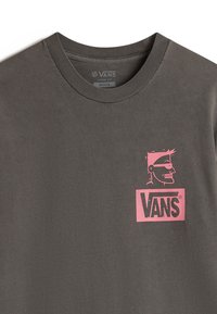 Šedé volné tričko s růžovým grafickým designem stylizované tváře a nápisem "VANS" na hrudi. Měkký bavlněný materiál.