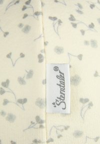 Weicher cremefarbener Stoff mit kleinen grauen Blumenmustern und einem weißen gewebten Etikett, das in der Mitte mit der Marke "Sterntaler" eingenäht ist.