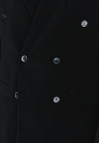 Czarny dwurzędowy płaszcz z sześcioma metalowymi guzikami ułożonymi w dwóch kolumnach, z bocznymi kieszeniami i klapami w kształcie notched.