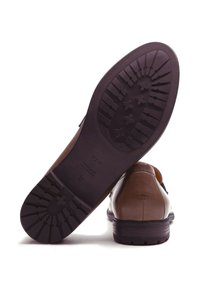 Scarpa in pelle marrone con superficie testurizzata, suola in gomma marrone con motivo del battistrada e marchio sulla parte inferiore.