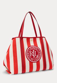 Rdeče in bele črtaste torba iz tkanine, ki ima na sprednji strani okrogle izvezeno logo, dvojne rdeče ročaje.