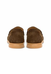 Bruine suède instappers met een gladde textuur, voorzien van een tan rubberen zool en eenvoudige stiksels, gezien vanaf de achterkant.