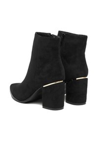 Czarne zamszowe botki za kostkę z ostrym noskiem, masywnym blokowym obcasem z złotymi akcentami oraz zamkiem błyskawicznym z boku dla łatwego zakładania.