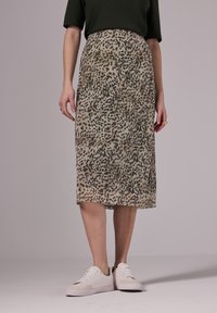 Midi sukně s leopardím potiskem v béžov�ých a zelených tónech, vyrobená z hladké látky a se střihovým stylem, doplněná bílými teniskami.