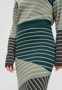 Gestreiftes Strickoberteil und Rockset in Grün, Grau und Weiß. Besitzt unterschiedlich dicke Streifen und einen taillierten Bund mit strukturiertem Strick.