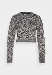 Korta tröja i svart och vit melerad stickning. Har långa ärmar, rundad halsringning och ett texturerat tyg.