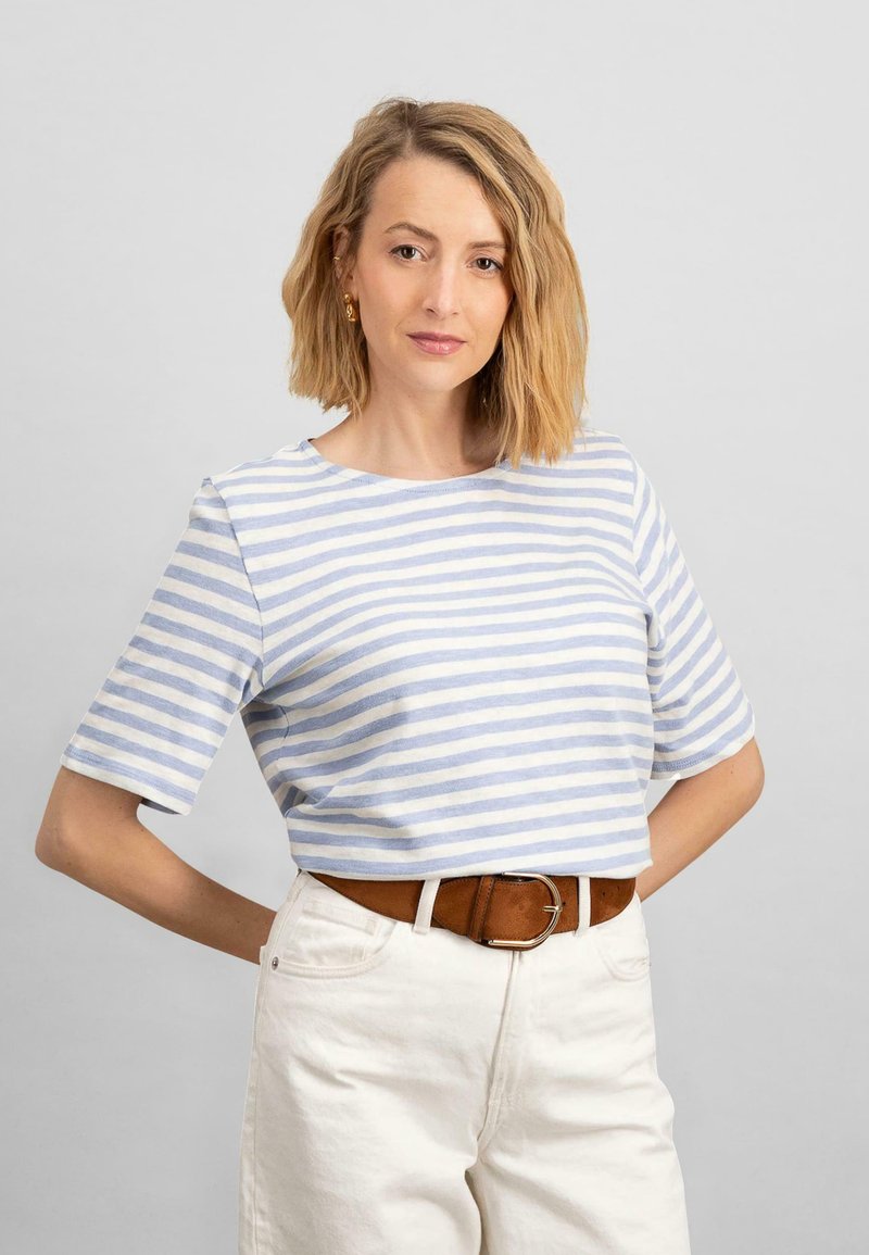 Modré a biele pruhované krátke rukávy crop top z mäkkého materiálu, skombinovaný so svetlými nohavicami a hnedým opaskom.