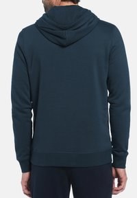 Donkerblauwe hoodie van zachte stof. Kenmerkt zich door lange mouwen, een kangoeroezak en een geribde boord en manchetten.