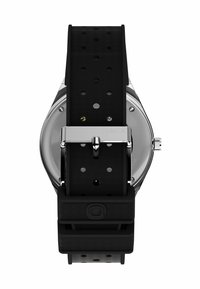 Black rubber watch strap with perforations and a silver stainless steel buckle. Round watch case with clear back, showcasing minimal details.