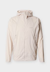 Chaqueta con capucha de color beige claro, con cremallera frontal, dos bolsillos laterales con cremallera, mangas largas y logotipo de Salomon en el pecho y la manga izquierda.