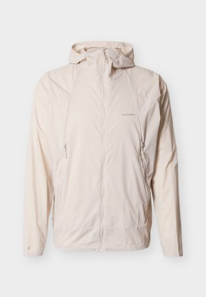 Lichtbeige capuchonvest met ritssluiting, twee ritssluitbare zijzakken, lange mouwen en Salomon-logo op de linkerborst en mouw.