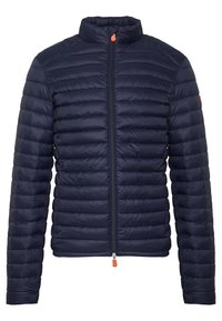 Mørkeblå polstret jakke med høj krave, lynlåslukning og orange lynlåstræk. Har vandrette syninger for tekstur og varme.