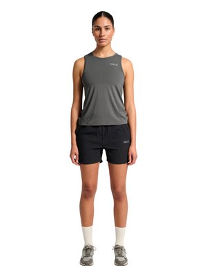 Vrouw draagt een grijze mouwloze top en zwarte shorts met het "HALO"-logo, staat rechtop, beige sokken en grijze sportschoenen op een witte achtergrond.