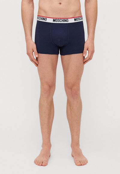 Marineblaue Boxershorts aus glattem Stoff mit einem elastischen Bund in Weiß und Rot, der das Logo "MOSCHINO" trägt. Figurbetonter Schnitt, mittlere Oberschenkellänge.