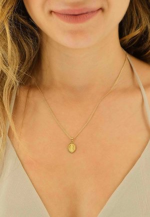 Goldene Halskette mit feiner Kette, mit einem ovalen Anhänger mit detailliertem Design, der auf nackter Haut liegt. Einfach und elegant.