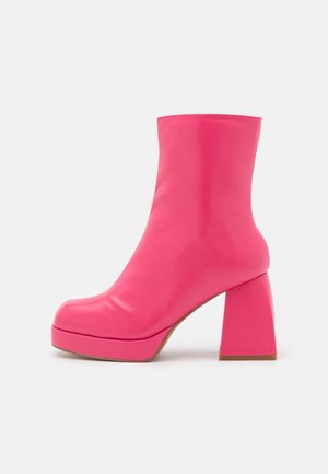 Bottine en cuir rose vif avec un talon bloc et une semelle plateforme sur fond blanc, vue de côté.