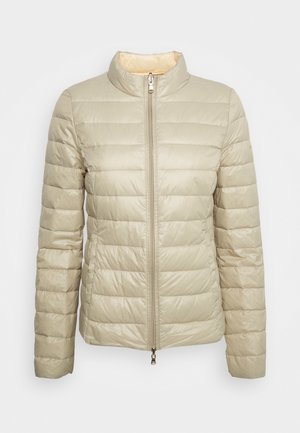 Veste matelassée beige légère avec col montant et fermeture éclair double sens à l'avant, conçue pour la chaleur et un port décontracté.