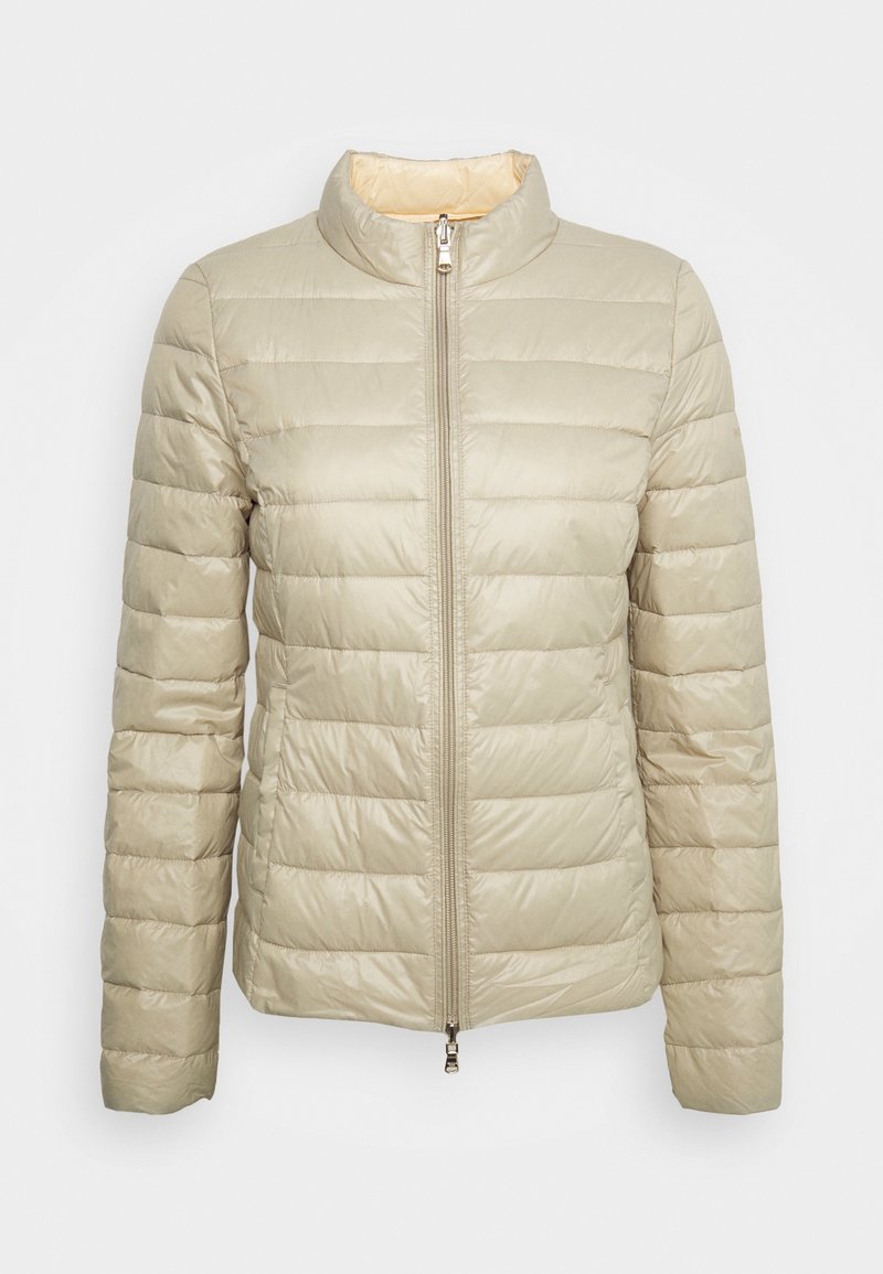 Veste matelassée beige légère avec col montant et fermeture éclair double sens à l'avant, conçue pour la chaleur et un port décontracté.
