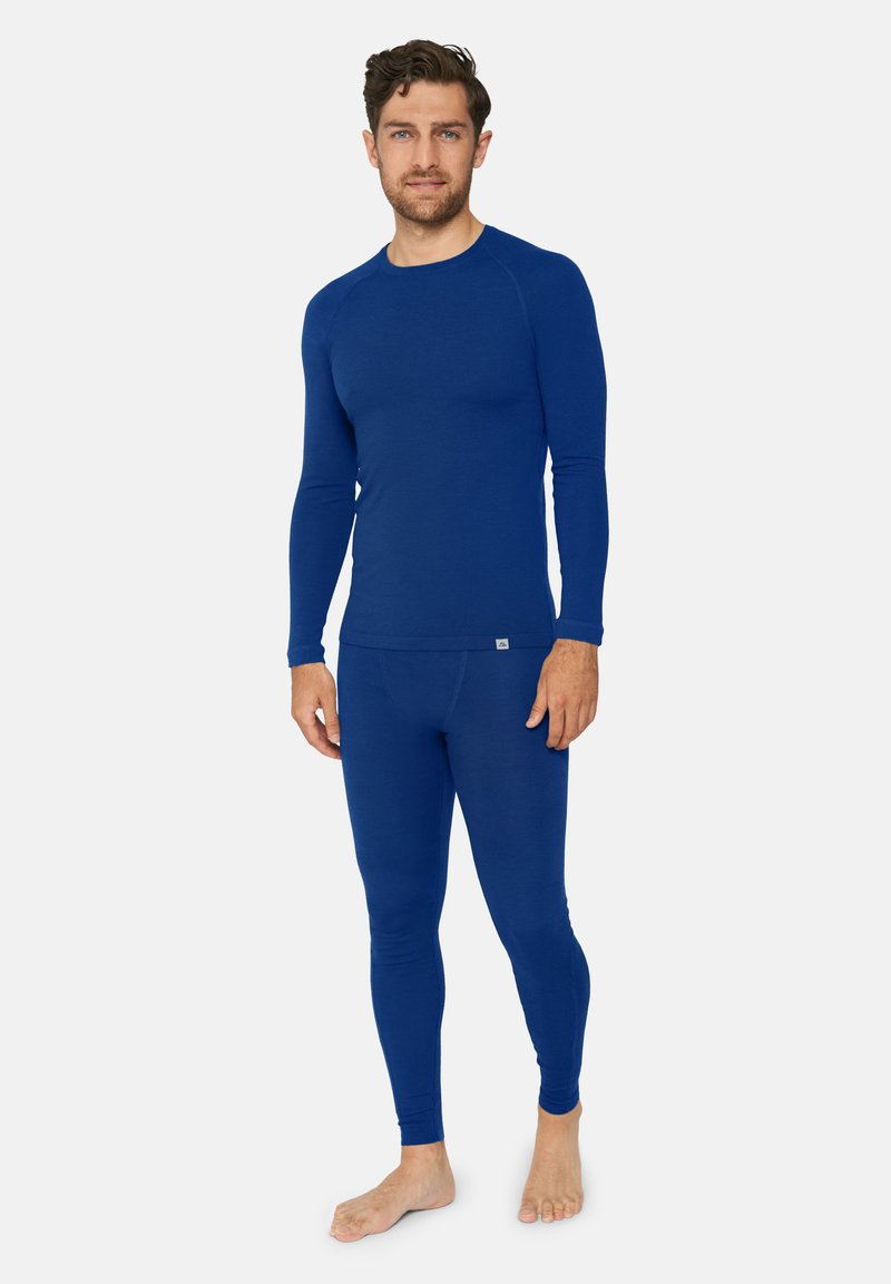 Blandet basislag i blå bestående af en langærmet top og tætsiddende leggings lavet af glat, strækbart materiale. Minimal branding.